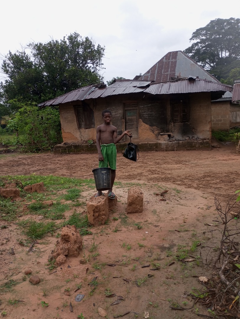 A boy carrying buckets of water fetched from a stream.