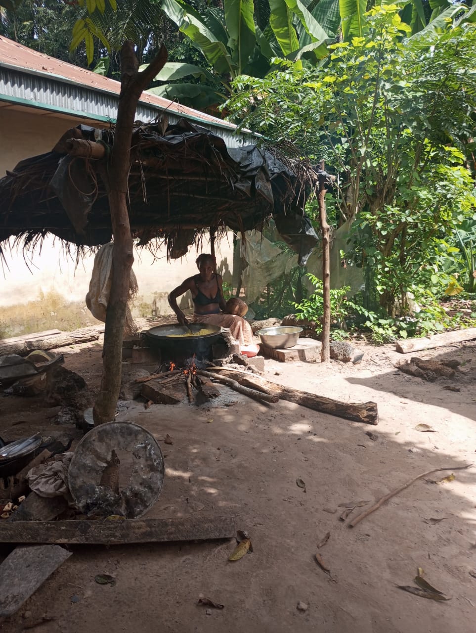 A woman minding the cooking food in the outdoor kitchen.